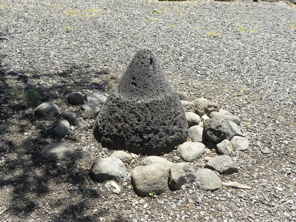 Cone-shaped black basalt millstone among stones