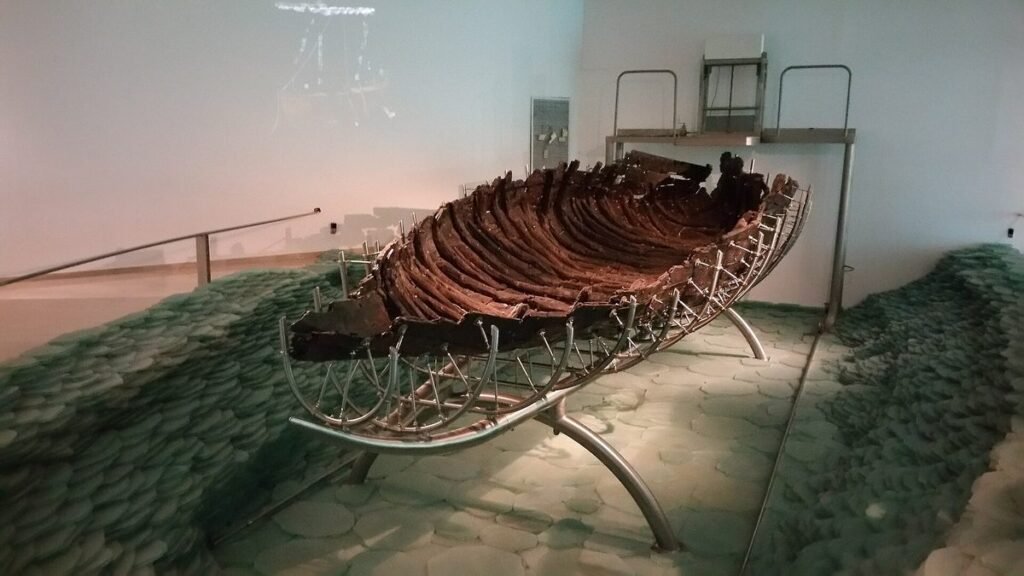 Wooden hull of an ancient fishing boat on a metal frame in a museum
