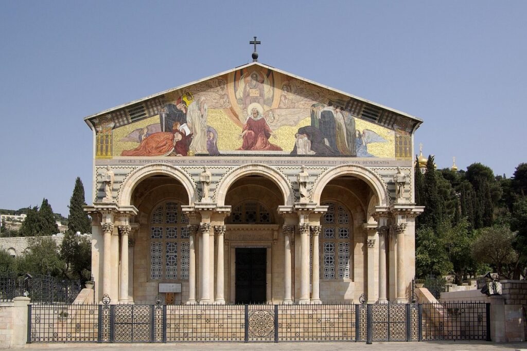 Facade of the Church of All Nations with a portico of columns and a golden mosaic